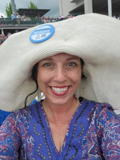 Headshot of Chanell Lowery at a horse derby in a paisley top and a wide-brimmed hat